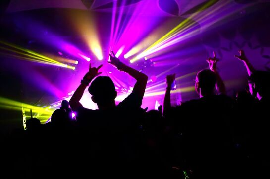 People dancing in dark room backlit with yellow and purple DJ lights Picture