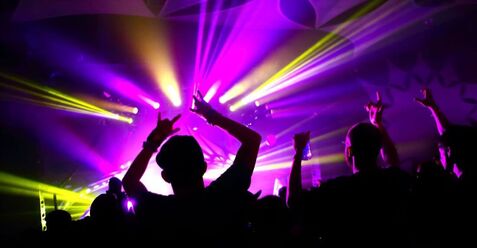 People dancing with colorful DJ lights in background Picture
