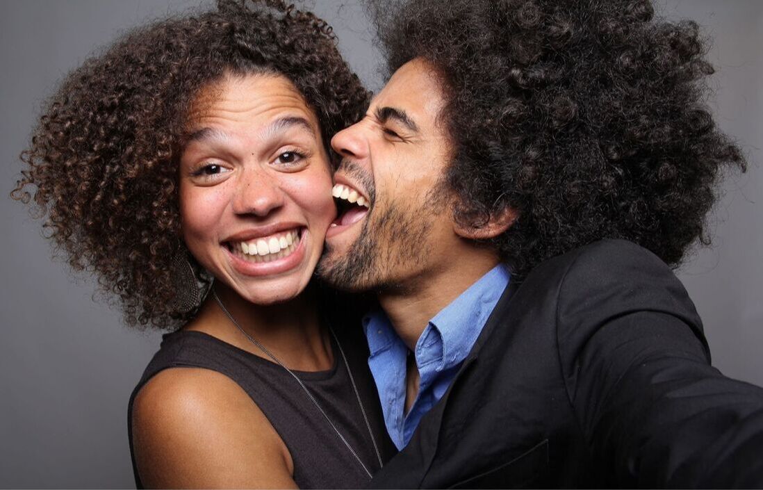 Really funny photo booth pose of man pretend biting woman's cheek with big smiles Picture
