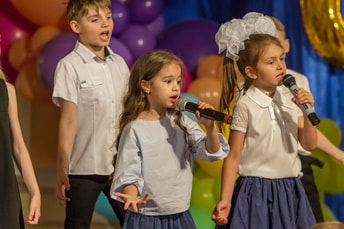 Adorable kids singing into microphones in school play Picture