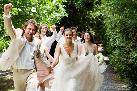 Happy wedding party charging down a path with bouquets Picture