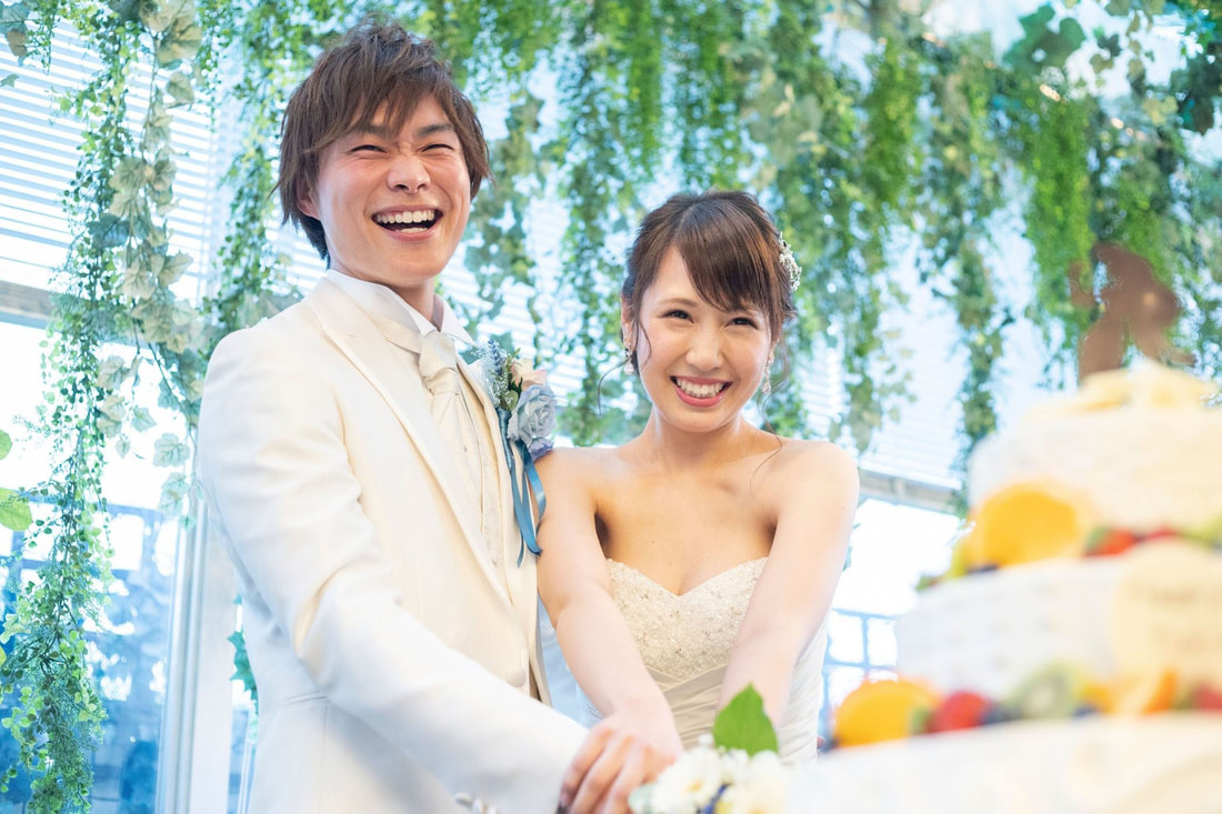 Joyful Asian couple cutting wedding cake  Picture